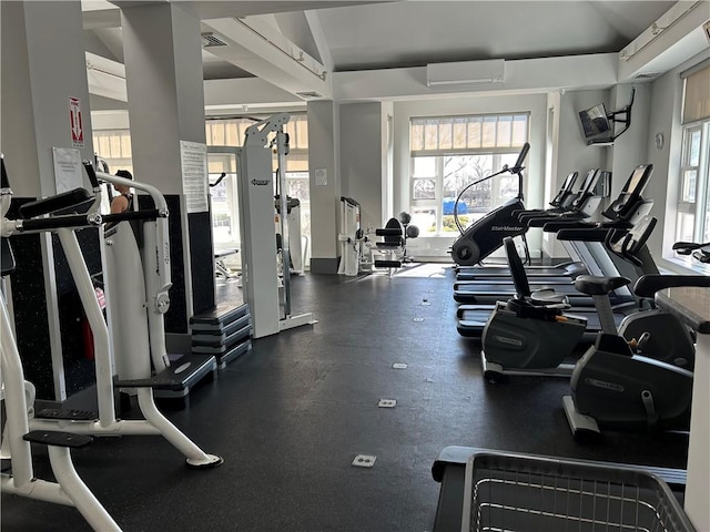 gym with visible vents, lofted ceiling, and a wall unit AC