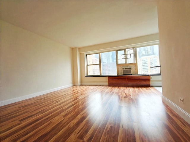 unfurnished living room featuring a fireplace, wood finished floors, a wealth of natural light, and baseboards