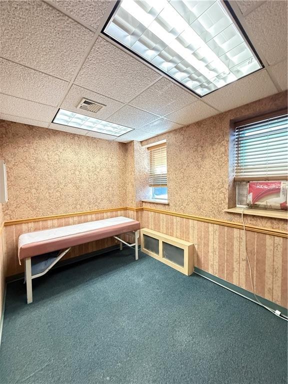 misc room with a paneled ceiling, wallpapered walls, and visible vents