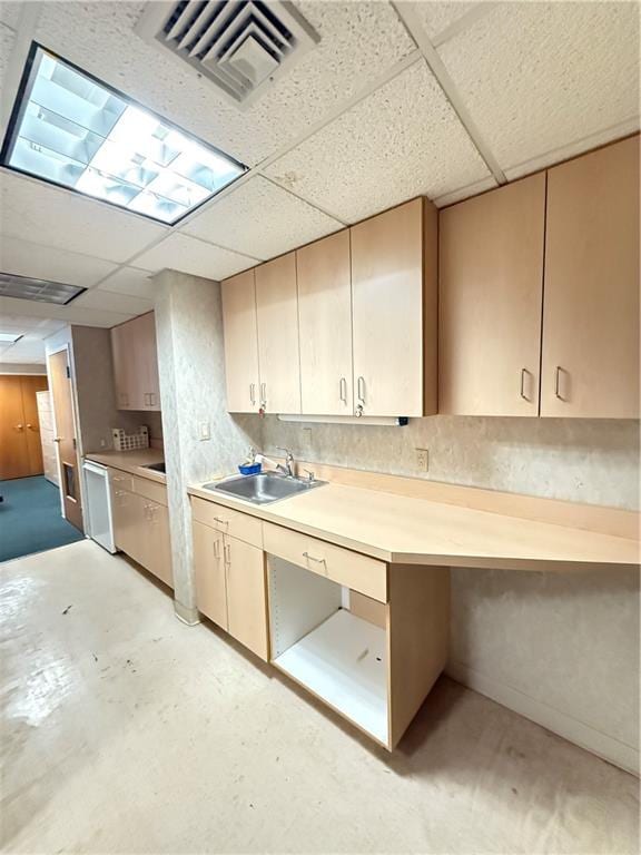 kitchen with a drop ceiling, concrete floors, a sink, visible vents, and light countertops