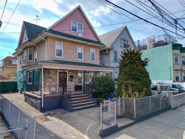 view of front facade with a porch, a gate, stone siding, and a fenced front yard