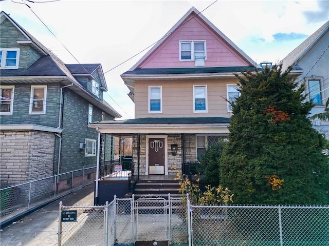 american foursquare style home featuring a fenced front yard, covered porch, and a gate