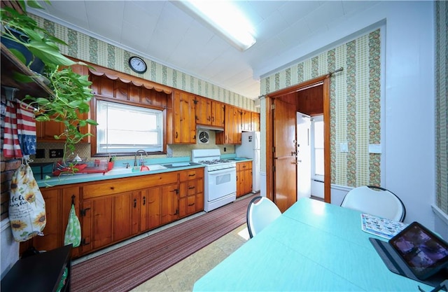 kitchen featuring white appliances, a sink, and wallpapered walls