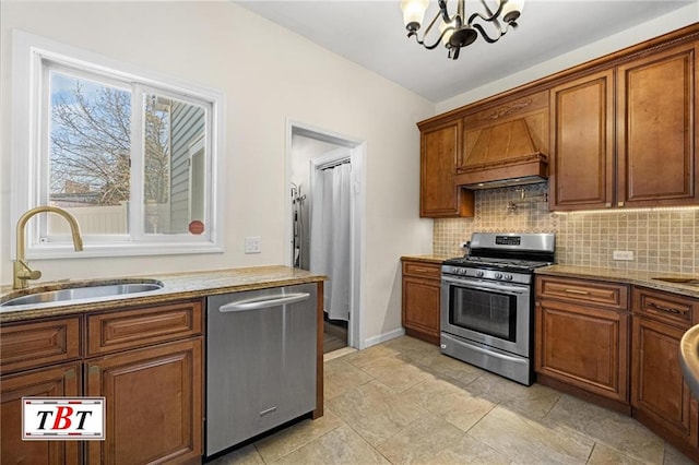 kitchen featuring a notable chandelier, tasteful backsplash, appliances with stainless steel finishes, brown cabinetry, and a sink