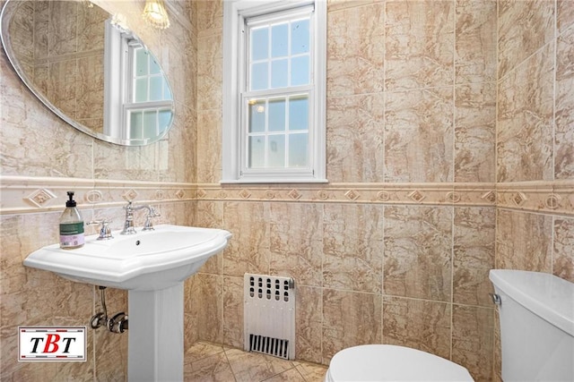 bathroom featuring radiator, toilet, and tile walls