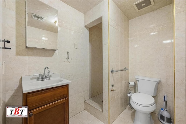 bathroom featuring tile patterned flooring, visible vents, vanity, tile walls, and a stall shower