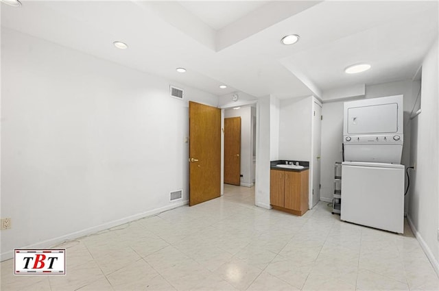 unfurnished room with stacked washer / dryer, recessed lighting, and baseboards