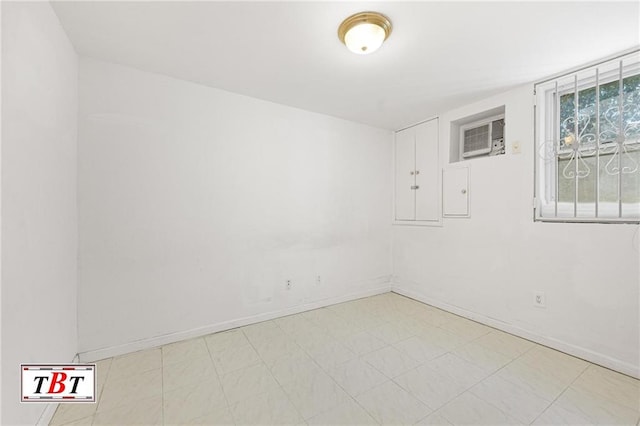 empty room with light floors, baseboards, and a wall mounted air conditioner
