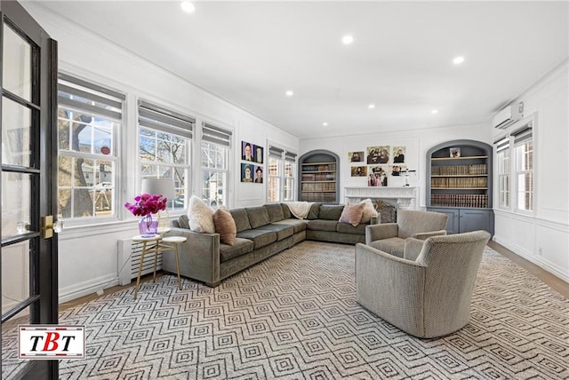 living area with baseboards, built in features, a high end fireplace, an AC wall unit, and recessed lighting