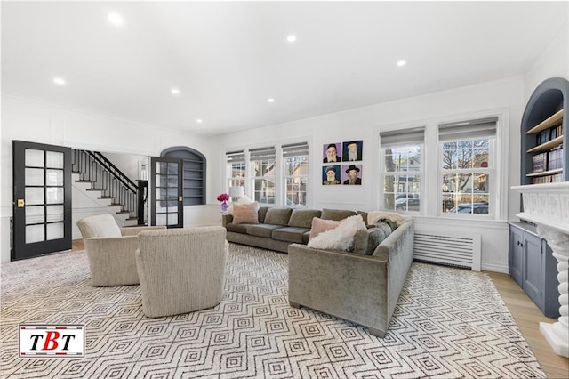 living room with arched walkways, recessed lighting, stairway, light wood-type flooring, and radiator