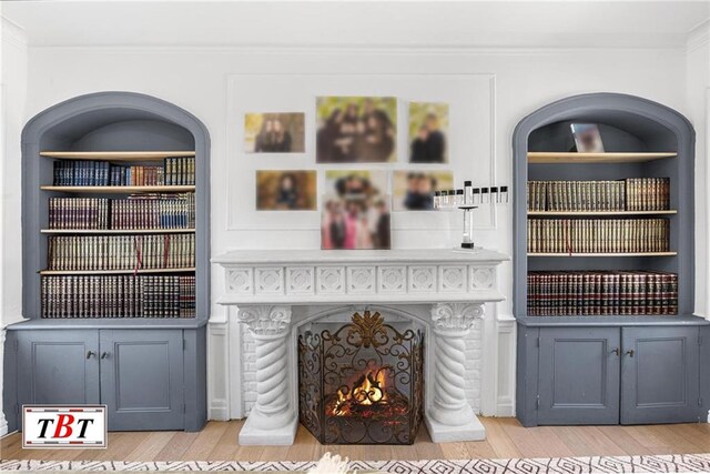 living area with light wood-type flooring, crown molding, and a warm lit fireplace