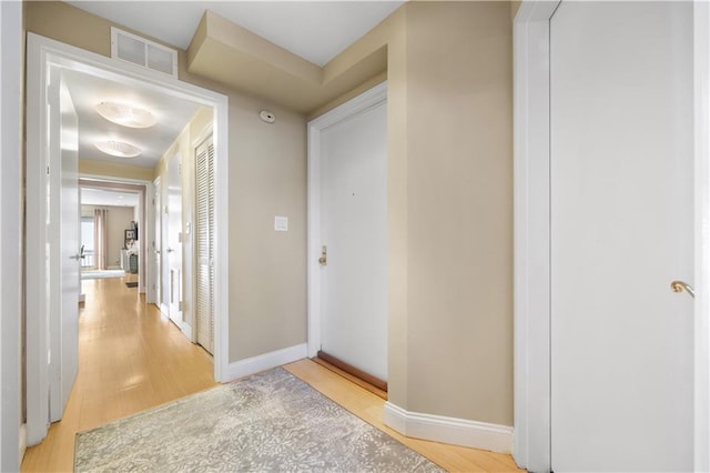 corridor featuring light wood-type flooring, visible vents, and baseboards