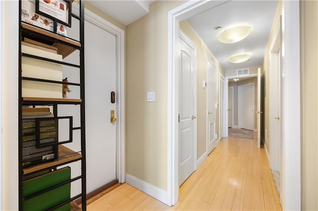 hallway featuring light wood-type flooring, visible vents, and baseboards