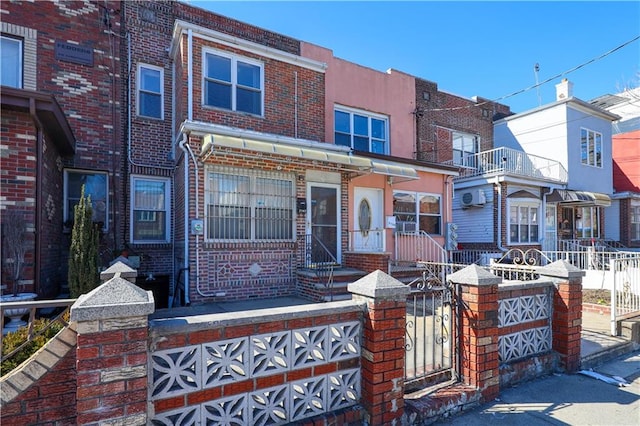 multi unit property featuring a fenced front yard and brick siding