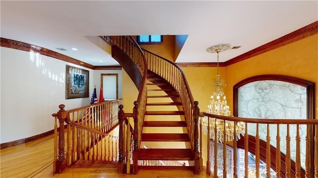 stairs with baseboards, visible vents, ornamental molding, wood finished floors, and a chandelier