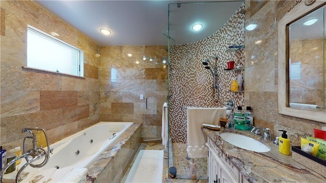 full bath featuring a whirlpool tub, a tile shower, tile walls, and vanity