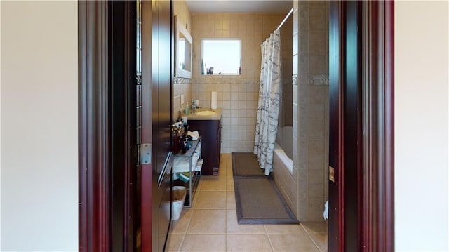 corridor featuring a sink, light tile patterned floors, and tile walls