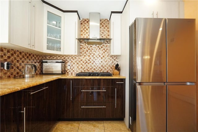 kitchen featuring wall chimney range hood, white cabinets, dark brown cabinets, and freestanding refrigerator