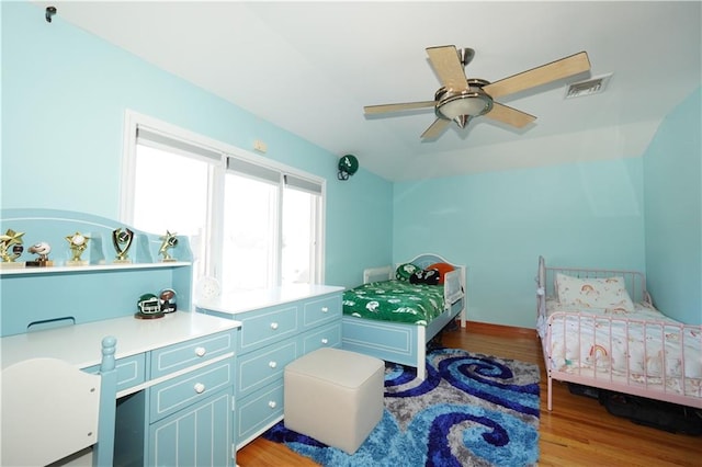 bedroom featuring vaulted ceiling, ceiling fan, wood finished floors, and visible vents