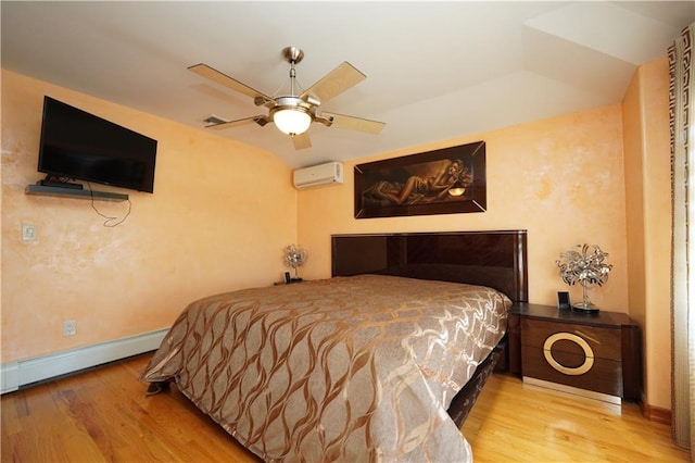 bedroom with baseboards, a baseboard heating unit, wood finished floors, and a wall mounted air conditioner