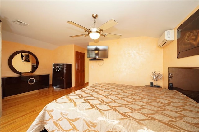 bedroom featuring visible vents, lofted ceiling, ceiling fan, wood finished floors, and an AC wall unit