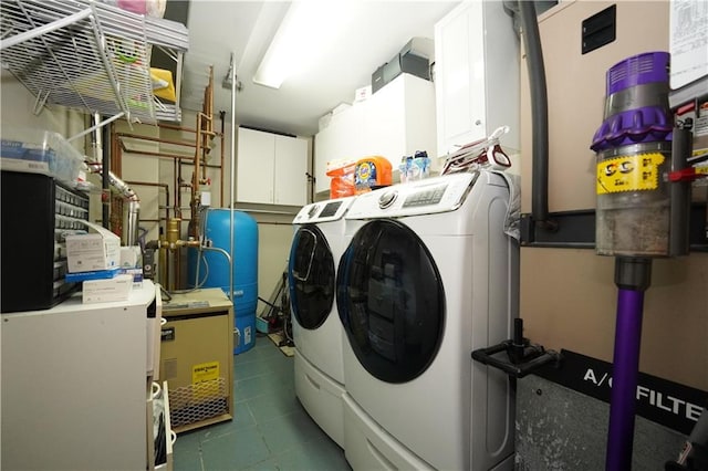 laundry area featuring separate washer and dryer, cabinet space, and tile patterned floors