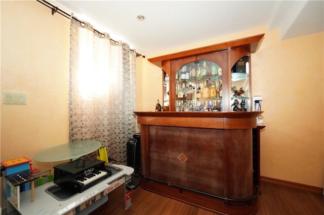 bar with a dry bar, baseboards, and wood finished floors