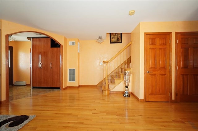 entrance foyer featuring arched walkways, visible vents, and wood finished floors