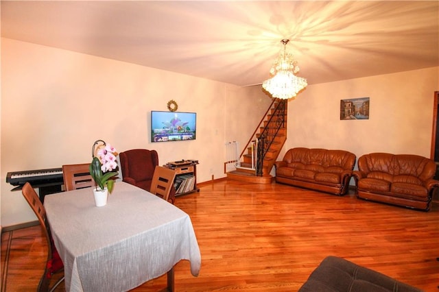 dining space featuring stairs, baseboards, wood finished floors, and an inviting chandelier