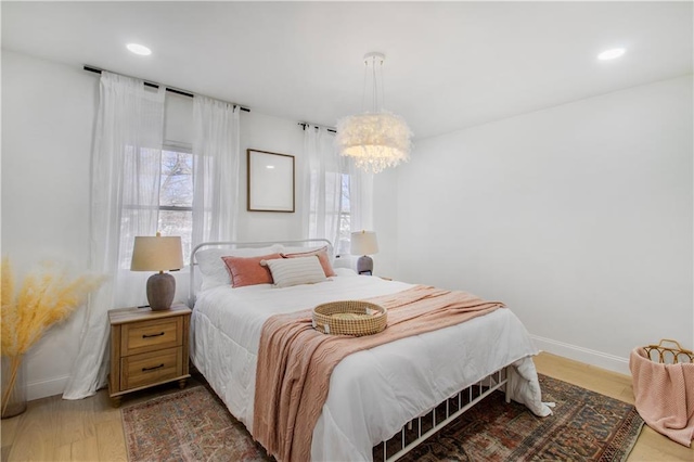 bedroom with a notable chandelier, baseboards, wood finished floors, and recessed lighting