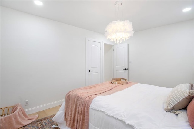 bedroom with an inviting chandelier, light wood-style flooring, baseboards, and recessed lighting