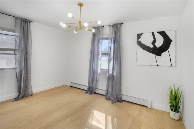 spare room with baseboard heating, a notable chandelier, baseboards, and wood finished floors