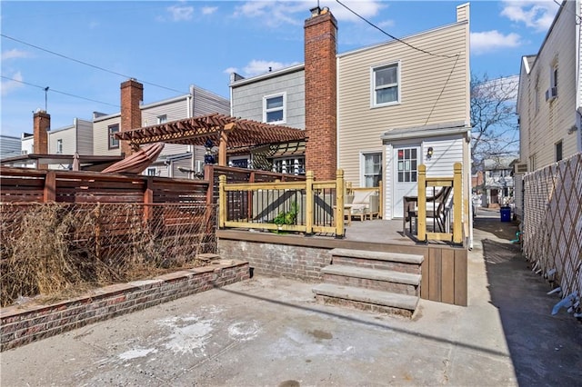 rear view of property featuring a patio area, fence, a pergola, and a wooden deck