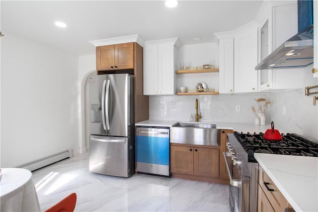 kitchen with a baseboard radiator, a sink, marble finish floor, appliances with stainless steel finishes, and wall chimney range hood