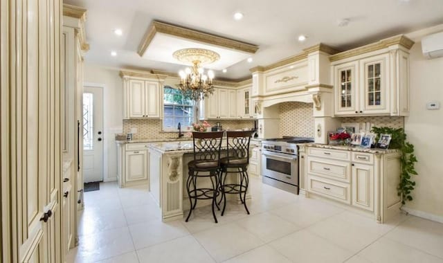 kitchen featuring tasteful backsplash, light stone counters, a breakfast bar, cream cabinets, and stainless steel stove