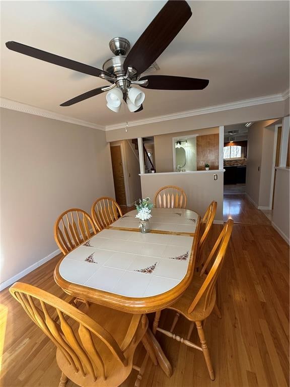 dining area featuring ornamental molding, baseboards, and wood finished floors