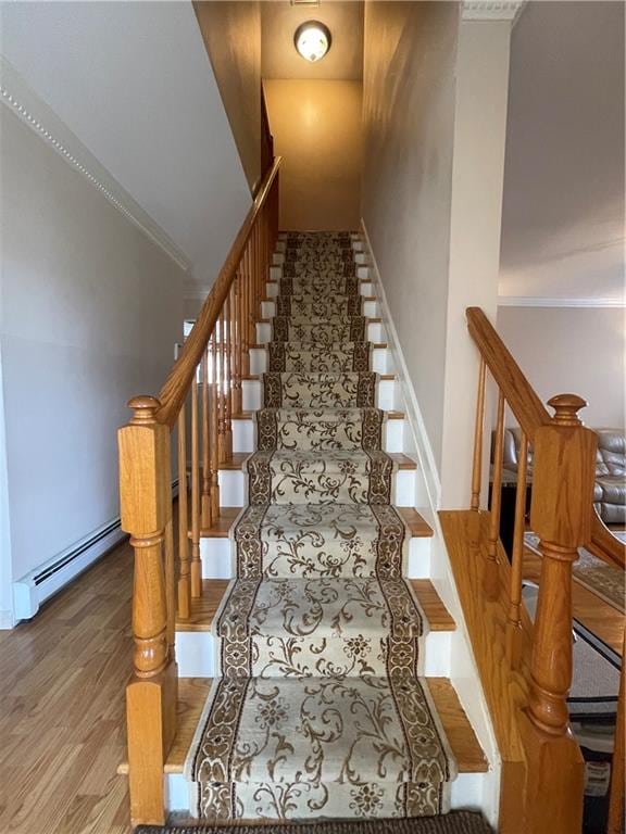 stairway featuring baseboards, baseboard heating, and wood finished floors