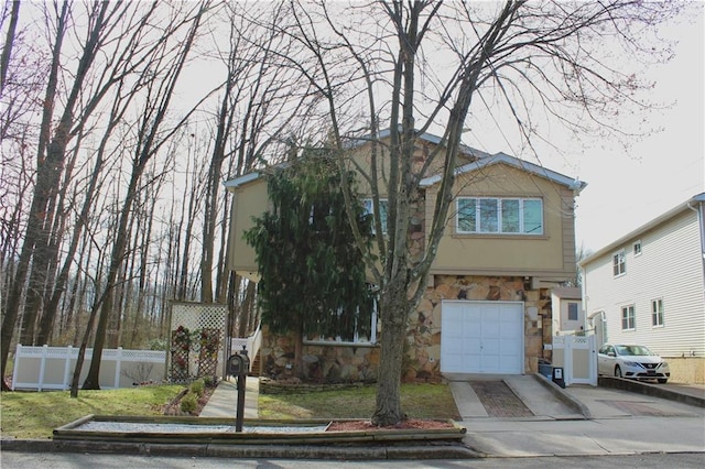 view of front of home featuring driveway, stone siding, an attached garage, fence, and stucco siding