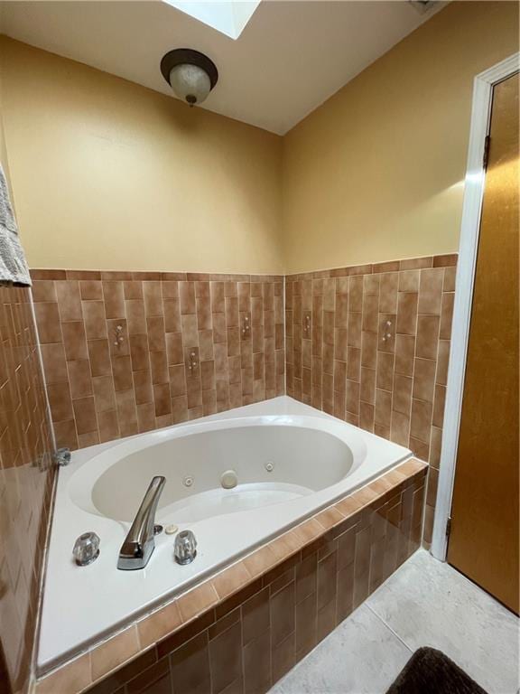 bathroom with a whirlpool tub, a skylight, and tile patterned flooring