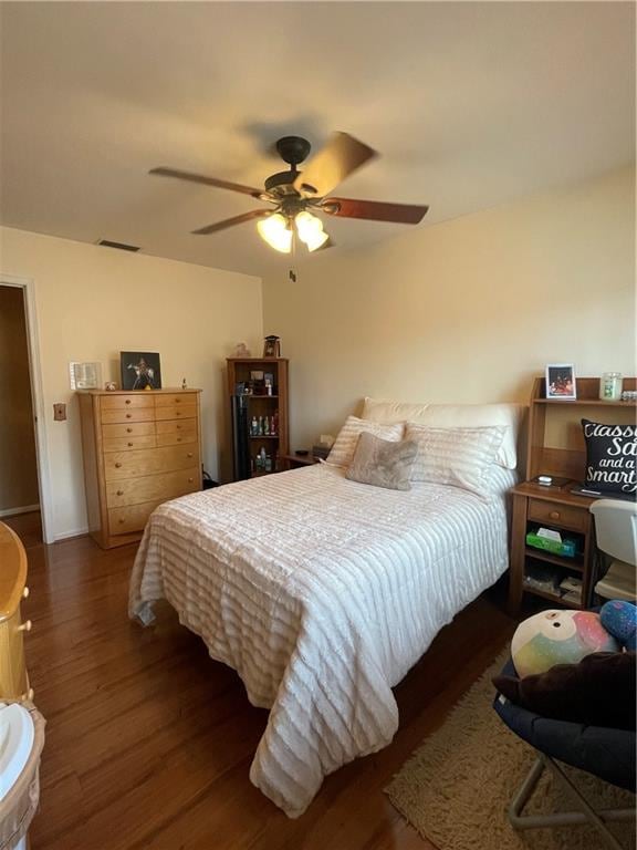 bedroom with ceiling fan, visible vents, and wood finished floors