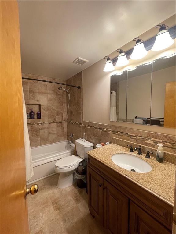 bathroom with toilet, shower / tub combo, visible vents, vanity, and tile walls