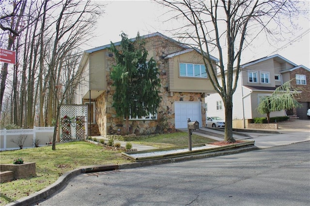 view of front of house with a garage, a front yard, stone siding, and fence