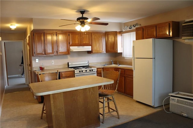 kitchen with white appliances, light countertops, under cabinet range hood, and a breakfast bar area