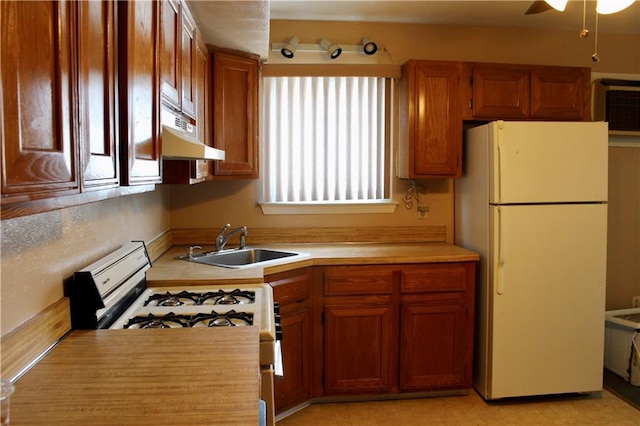 kitchen featuring brown cabinets, light countertops, a sink, white appliances, and under cabinet range hood