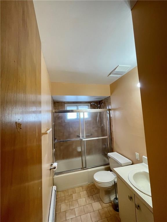 bathroom featuring toilet, vanity, visible vents, combined bath / shower with glass door, and baseboard heating