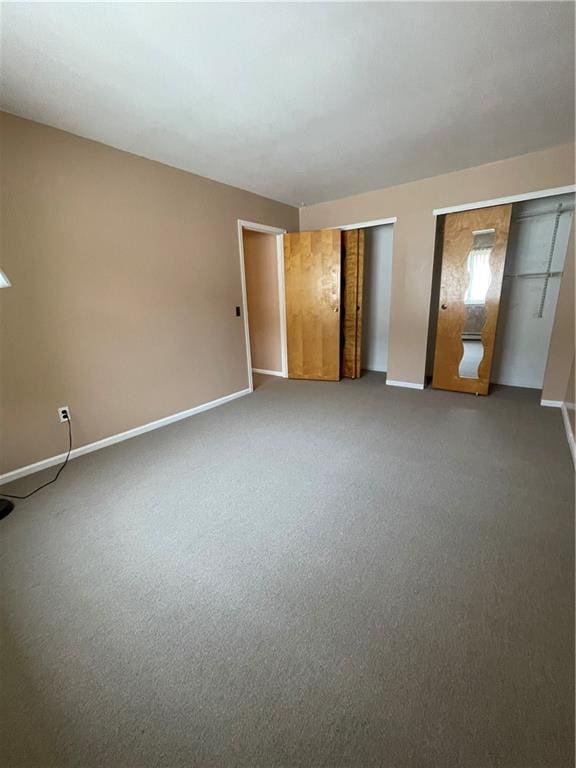 unfurnished bedroom with carpet, two closets, and baseboards