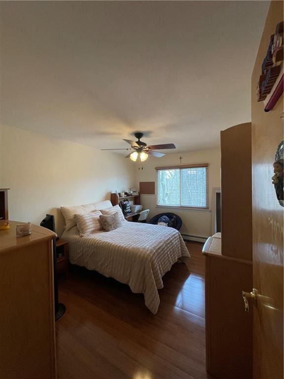 bedroom featuring ceiling fan, baseboard heating, and dark wood finished floors