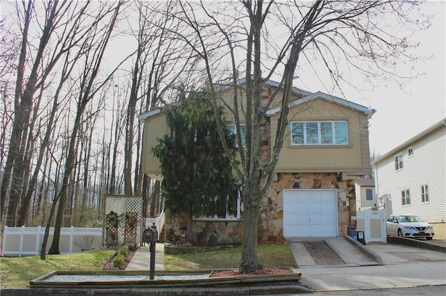 view of front of home featuring fence, stone siding, driveway, stucco siding, and a front yard