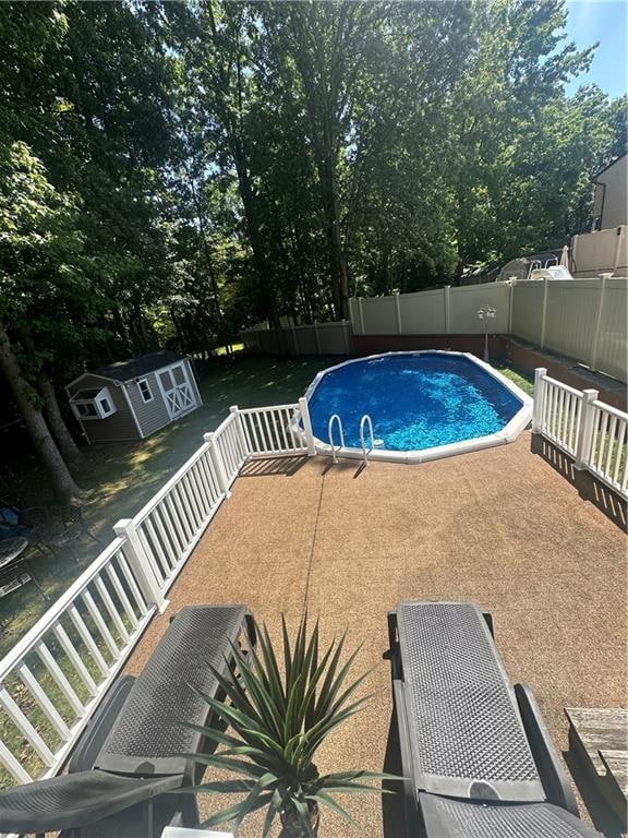 view of pool featuring a fenced in pool, an outbuilding, a fenced backyard, and a patio