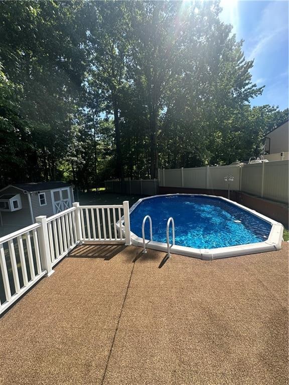 view of swimming pool with an outbuilding, a fenced backyard, a patio, and a storage shed